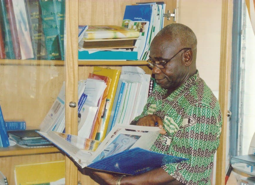 Ebenezer reading through files at his office bookshelf