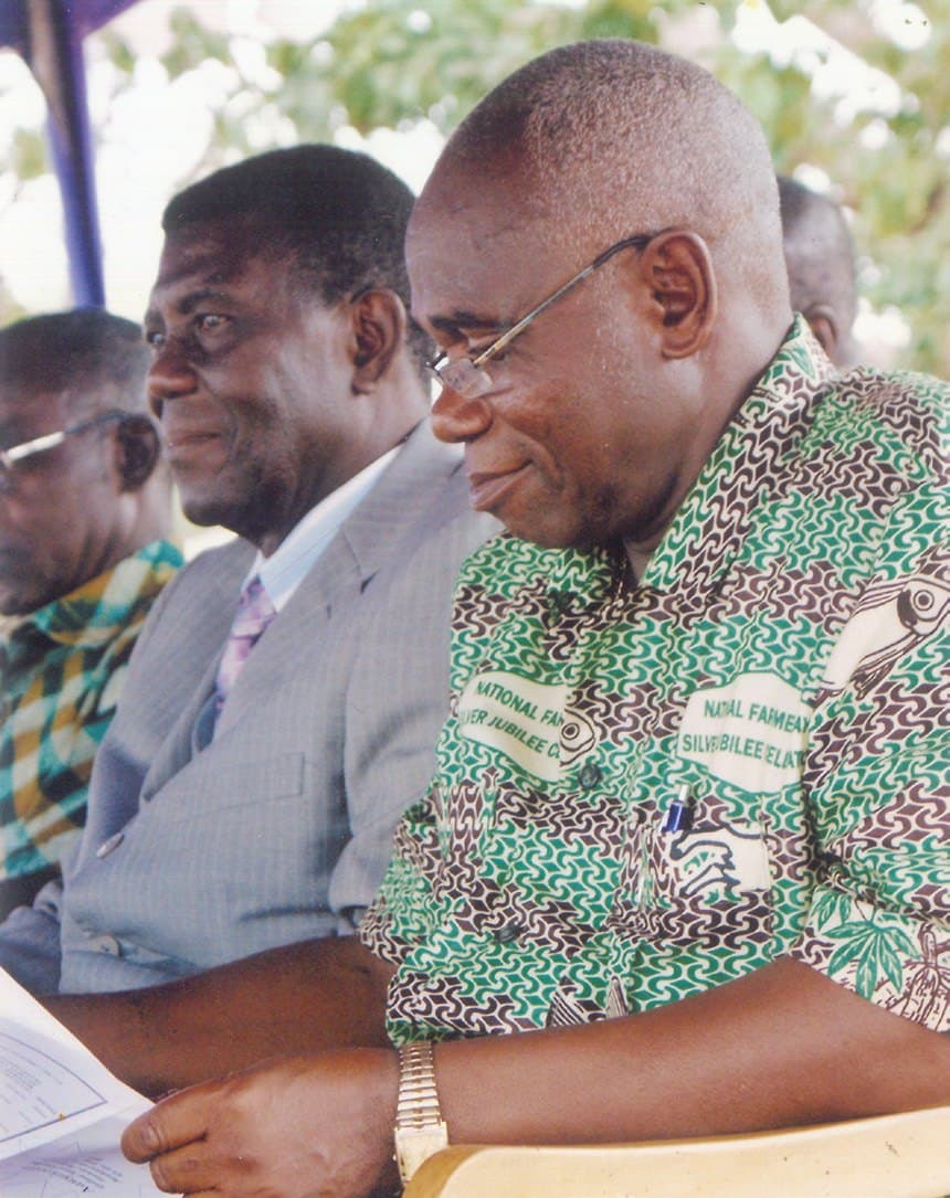 Ebenezer smiling at a meeting in a green printed shirt