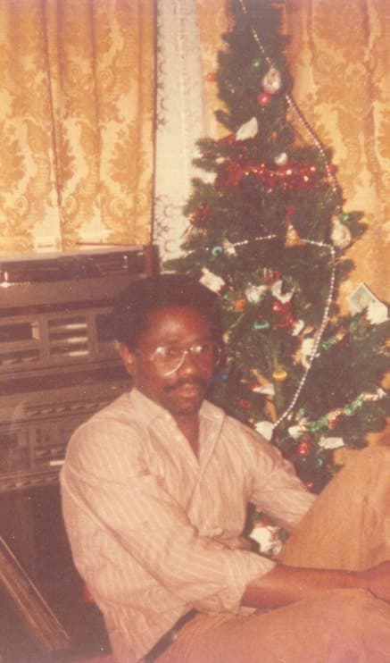 Ebenezer seated beside a Christmas tree